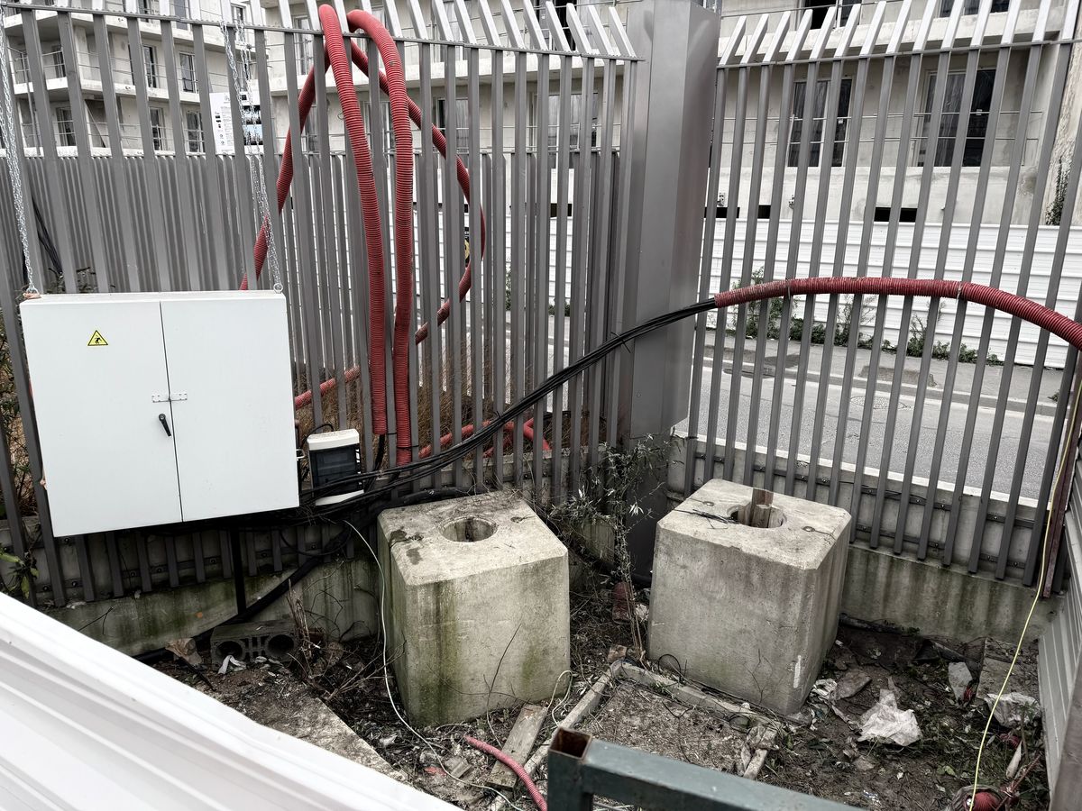 Armoire électrique de chantier et câbles d'alimentation derrière une palissade